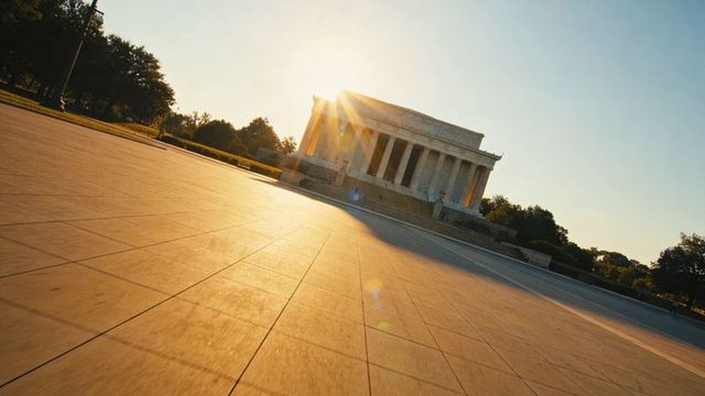 Lincoln memorial at golden hour with sunburst over expansive tiled plaza and copy space