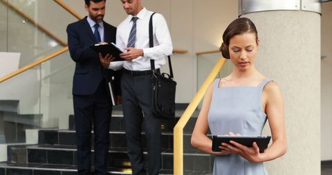 Confident businesswoman using tablet in busy office environment