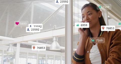 Young professional woman talking on smartphone by office glass with engagement badges
