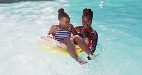 Mother and daughter enjoy swimming pool in summer day