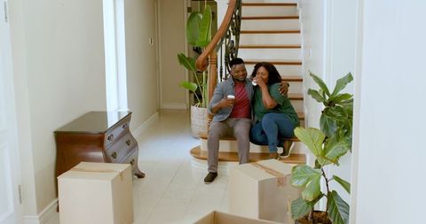 Joyful Couple Relaxing on Staircase with Coffee in New Home