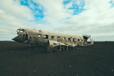 Abandoned Plane Wreck on Black Sand Beach Under Cloudy Sky