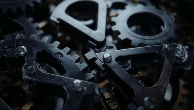 Close-up of meshing black gears with steel bolts