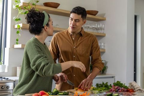 Couple preparing fresh vegetables together in sunlit modern kitchen, cozy home cooking moment
