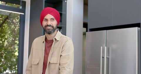 Smiling Man in Red Turban Relaxing in Modern Home Kitchen
