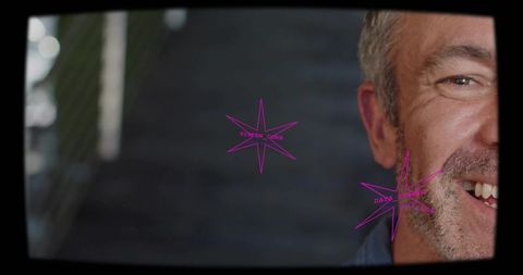 Smiling mature man half face facing stairwell through viewfinder with magenta stars