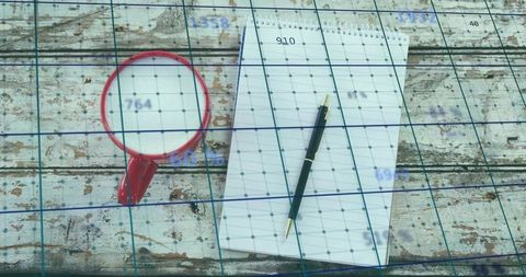 Rustic workspace with spiral notepad, black ballpoint pen and red mug on weathered wood