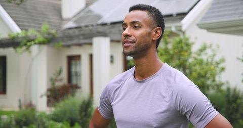 African american man living eco-friendly standing by sustainable modern house