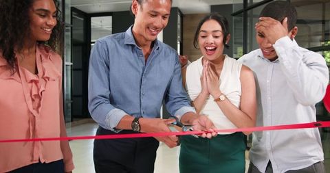 Diverse team celebrating office opening with ribbon cutting ceremony