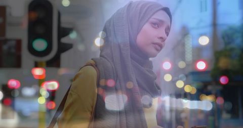 Asian Woman in Hijab Using Smartphone with Urban Lights