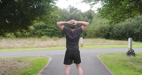 Man jogging in park with lush foliage on sunny day