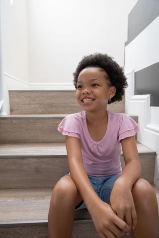 Joyful Girl Smiling on Home Stairs with Striped Accent Wall