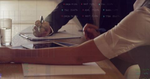 Reviewing tablet and discussing analytics during business meeting at wooden table