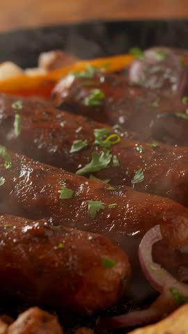 Sizzling Sausages Browning in Cast Iron Skillet with Onions and Parsley | Vertical Food Video