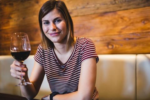 Woman Enjoying Red Wine at Cozy Restaurant Booth