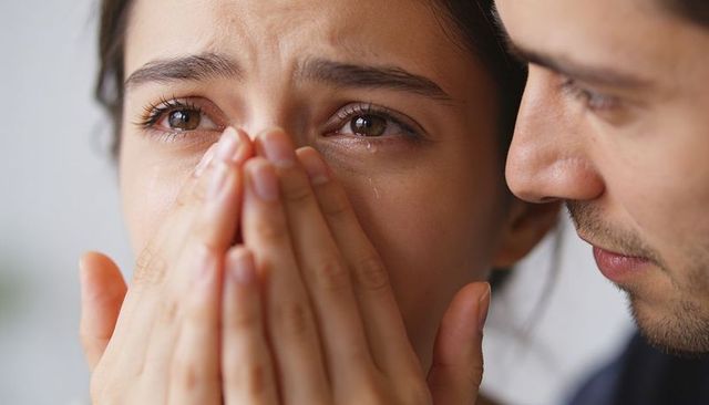 Tearful woman receiving comfort from partner in intimate closeup of emotional support