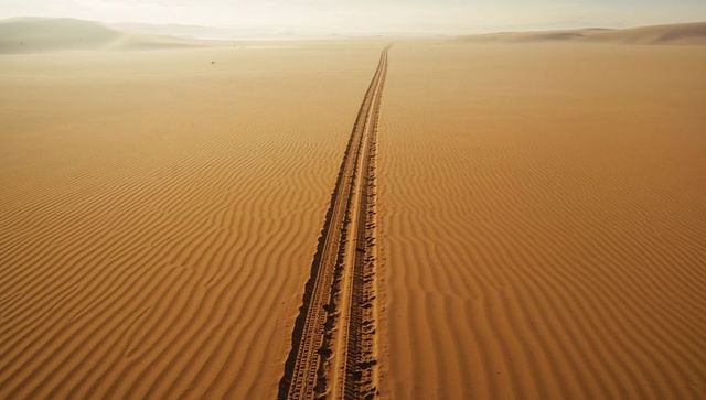 Endless tire tracks in desert landscape with rippling dune patterns