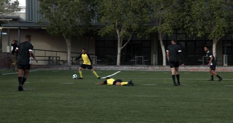 Group of boys playing soccer on school field in action
