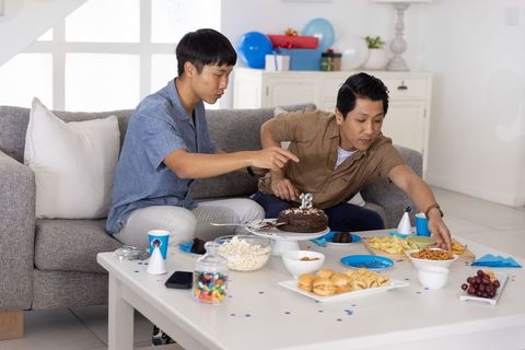 Asian friends celebrating 18th birthday at home with chocolate cake and snacks