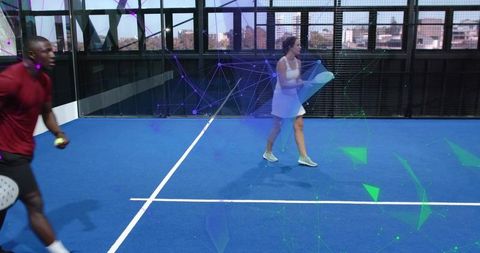 Female paddle player walking on blue urban court carrying towel with digital data overlay