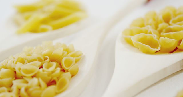 Closeup of Different Uncooked Pasta Shapes on Wooden Spoons - Download Free Stock Images Pikwizard.com