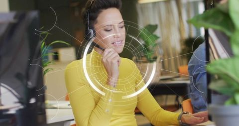 Customer support agent wearing headset using futuristic hud while gesturing in open office