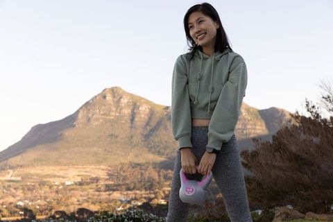 Woman Exercising Outdoors with Kettlebell in Scenic Mountain Landscape