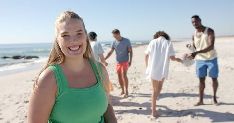 Smiling woman enjoying beach cleanup with friends on sunny day