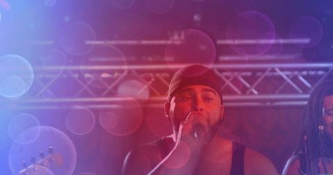 Male vocalist performing live on stage under colorful bokeh lighting and metal truss