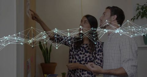 Two professionals analyzing notice board with network graphics