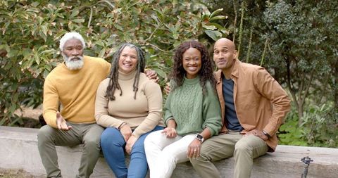 Multigenerational Black Family Enjoying Casual Outdoor Moment on Park Bench Showing Smartwatch