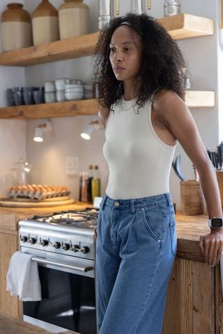 African american woman leaning on rustic kitchen counter near stove, cozy warm lifestyle