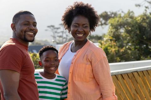 African american family smiling together on sunny wooden deck with railing overlooking green hills