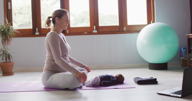 Mother practicing yoga with baby indoors on mat. Good for themes on parent-child bonding, home fitness routines, and illustrating healthy lifestyles for mothers. Can be used in articles on postpartum fitness, yoga practice for new moms, and wellness blogs.