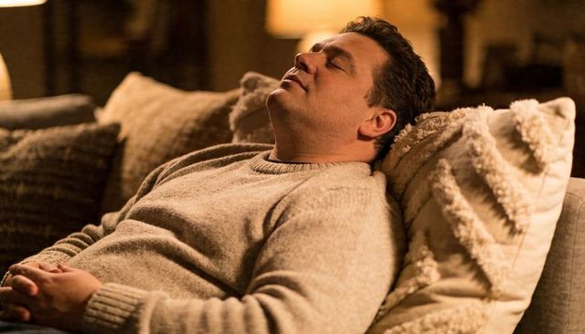 Man relaxing on sofa wearing beige sweater cozy living room evening relaxation scene