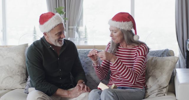 Mid-aged Couple celebrating Christmas at home, opening presents together - Download Free Stock Images Pikwizard.com