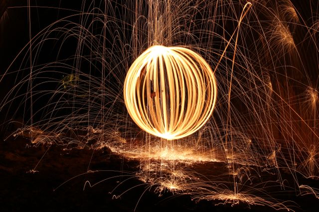 Sparks creating intricate light patterns in circular motion during night illustrates vibrant creation and artistic endeavor. Perfect for projects emphasizing energy, creativity, night photography, and long exposure techniques. Excellent for use in graphic design projects, advertising, or as a visual metaphor for energy and movement.