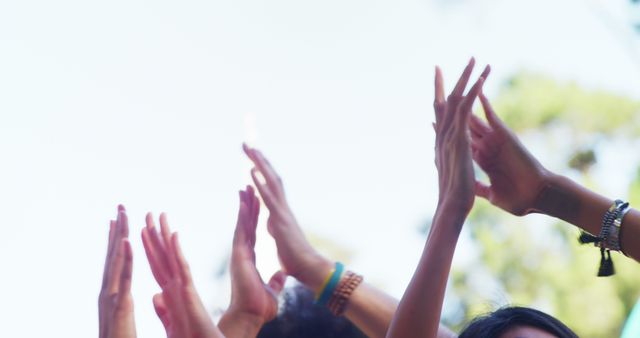 Group of people raising hands in unison outdoors, demonstrating unity and celebration. Ideal for content related to teamwork, community events, social gatherings, and positive vibes.