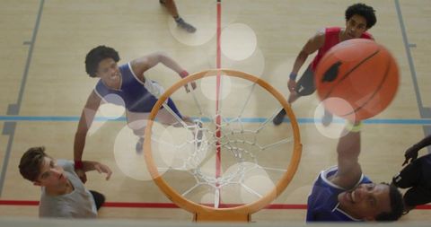 Overhead dunk action showing basketball slam through hoop on indoor court