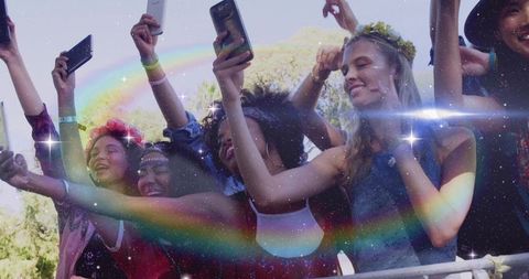 Front-row festival crowd raising phones, cheering and smiling with flower crowns