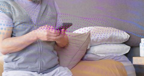 Man using smartphone in bed wearing hoodie and loungewear morning relaxation