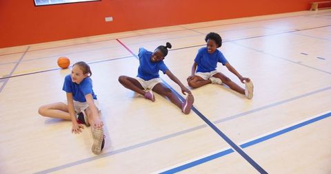 Girls Stretching Before Gym Practice on Indoor Court