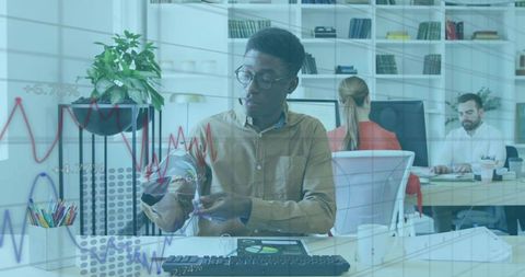 Young professional analyzing financial data on tablet with stylus in coworking office