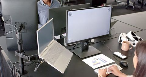 Professional using dual monitors for multitasking in modern office