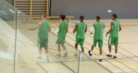 Five male basketball players warming up on school gym court practicing team drills