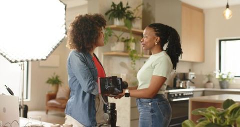 Female creators filming and collaborating in modern kitchen with gimbal and softbox