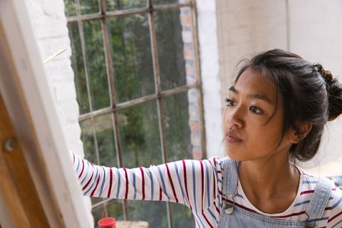 Young asian woman painting at easel in creative art studio