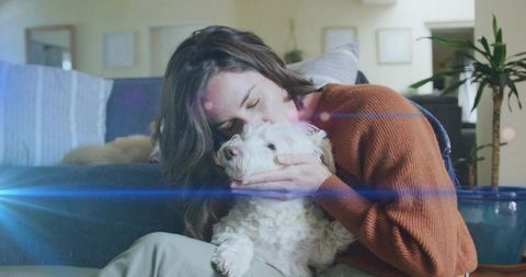 Woman Cradling and Kissing Dog at Cozy Home Interior
