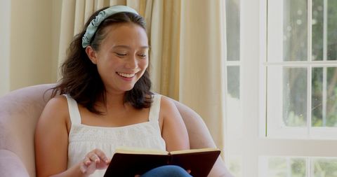 Smiling woman enjoying a book in cozy living room setting