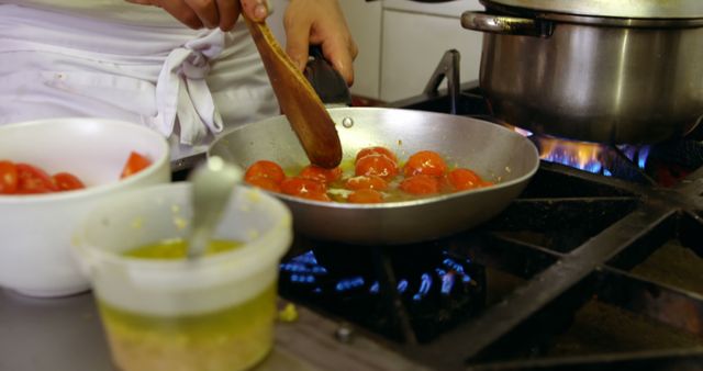 Close-up shot of chef cooking tomatoes in pan on stove, perfect for culinary blogs, cooking tutorials, restaurant promotions, food recipes, or any gastronomy-related marketing material.